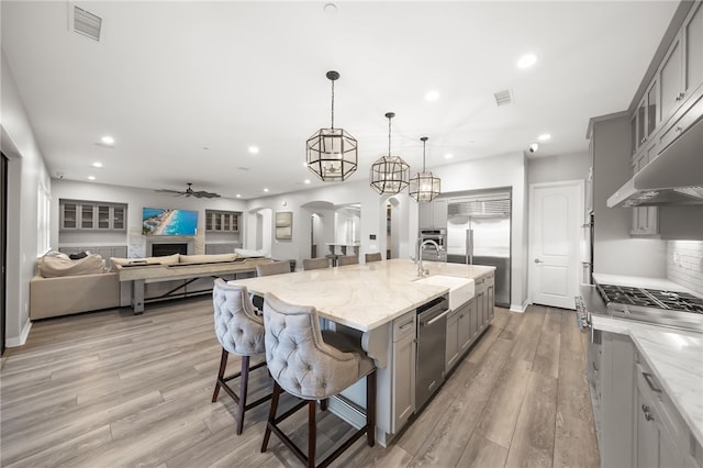 kitchen with arched walkways, a large island, gray cabinetry, open floor plan, and a kitchen bar