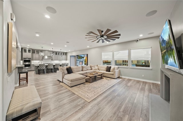 living area with ceiling fan, light wood-type flooring, baseboards, and recessed lighting