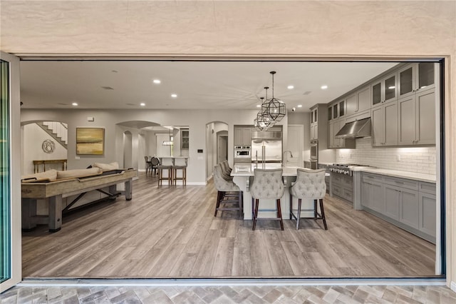 kitchen with hanging light fixtures, glass insert cabinets, light countertops, and open floor plan