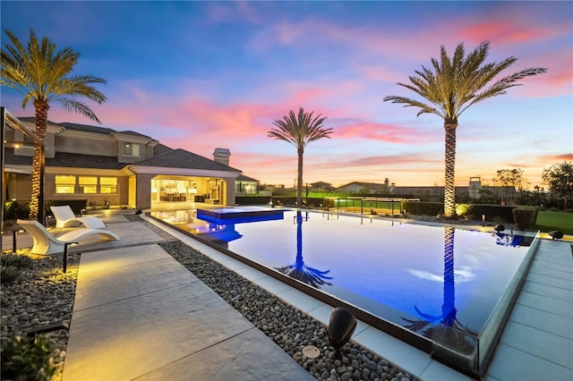 view of swimming pool with an infinity pool, a patio area, and fence