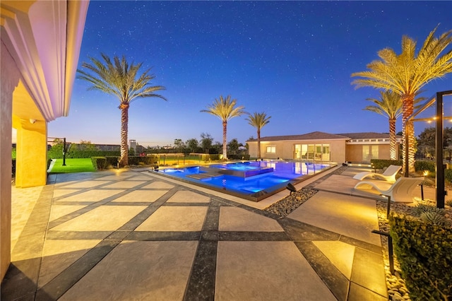 pool at dusk featuring an infinity pool, a patio area, and a jacuzzi