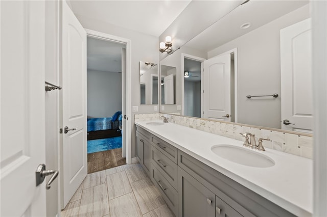 full bathroom with double vanity, a sink, and connected bathroom