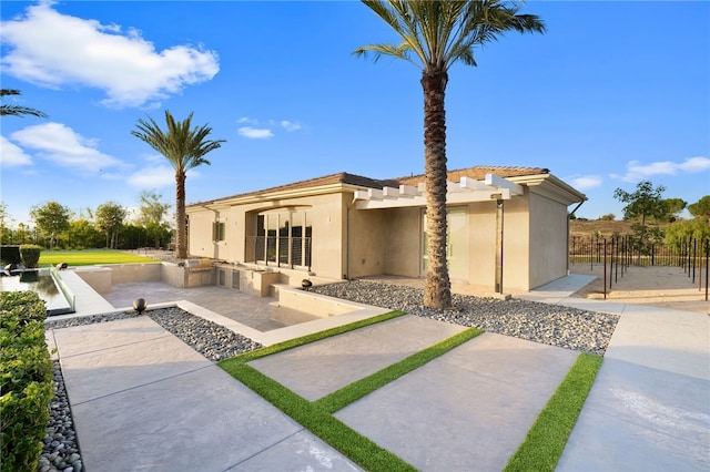 view of front of house with exterior kitchen, a patio, fence, and stucco siding