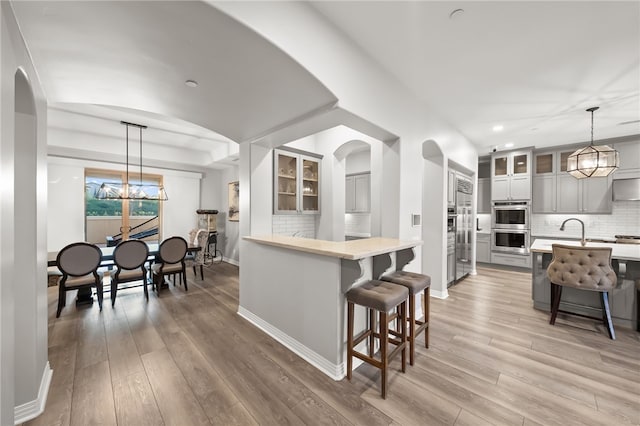 kitchen with a kitchen bar, glass insert cabinets, and light countertops