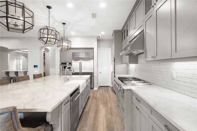 kitchen with gray cabinets, decorative light fixtures, a large island, and a kitchen bar