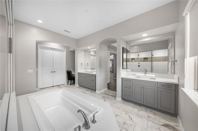 bathroom with marble finish floor, two vanities, a sink, and recessed lighting