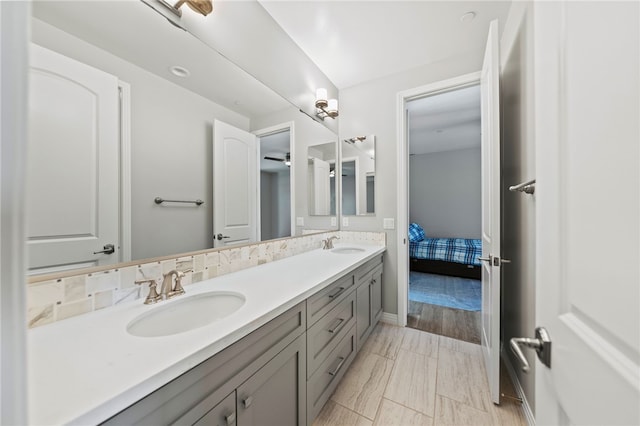 full bath with baseboards, a sink, ensuite bath, and double vanity