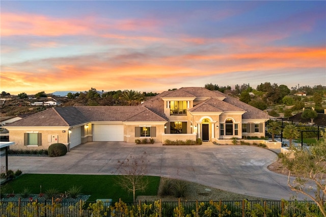 mediterranean / spanish-style home featuring concrete driveway, fence, an attached garage, and stucco siding