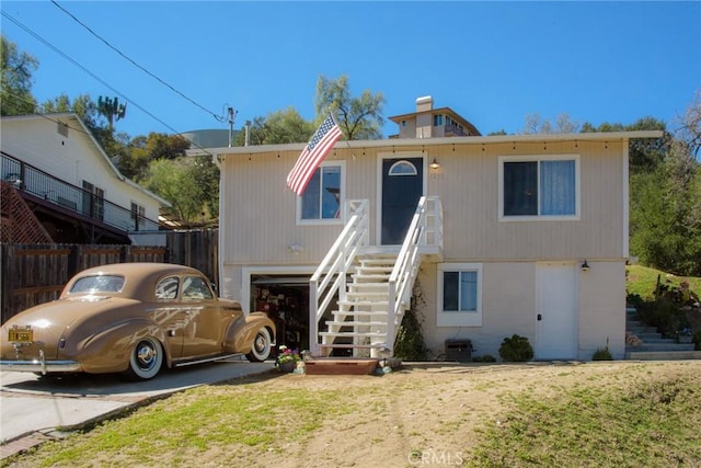 view of front facade with a garage, stairway, and fence