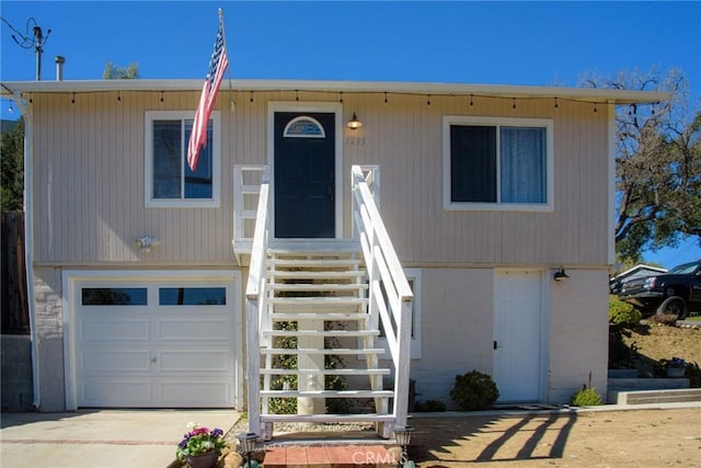 view of front of home featuring a garage, driveway, and stairs