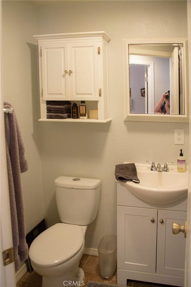 half bathroom featuring vanity, tile patterned flooring, toilet, and baseboards