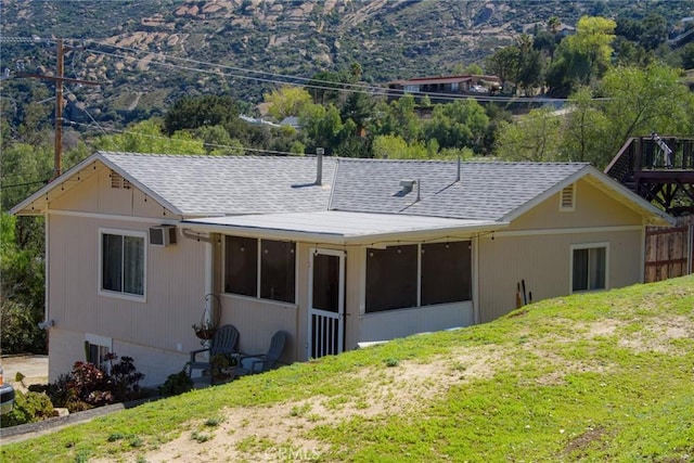 rear view of house featuring a shingled roof and a lawn