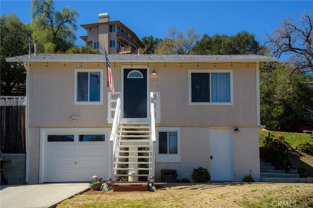 view of front of home with concrete driveway, stairway, and an attached garage