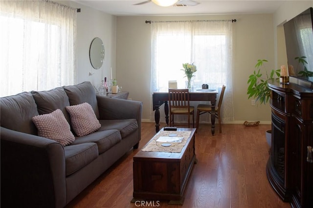 living room featuring dark wood-style floors, ceiling fan, and baseboards