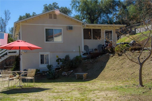 back of property featuring stairway and a lawn