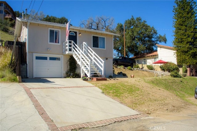 view of front facade with driveway, an attached garage, and stairs