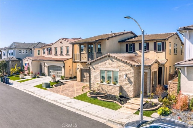 view of front of property featuring driveway, stone siding, a residential view, a tiled roof, and stucco siding