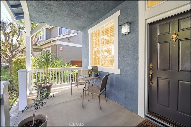 doorway to property featuring a porch and stucco siding