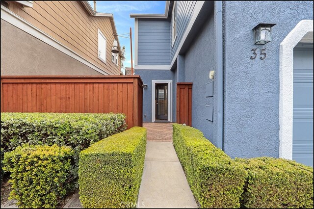 doorway to property with a garage and stucco siding