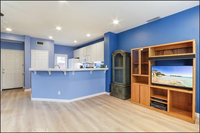 kitchen featuring light wood-type flooring, white appliances, visible vents, and white cabinets