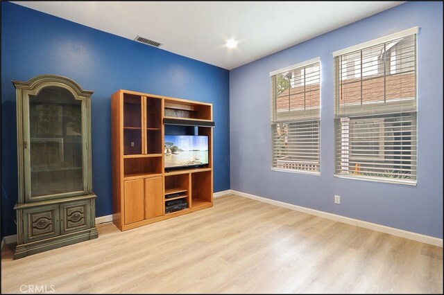 unfurnished room featuring baseboards, visible vents, and wood finished floors