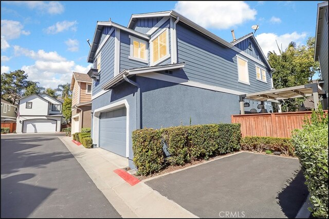 view of side of home with a pergola, an attached garage, fence, board and batten siding, and stucco siding