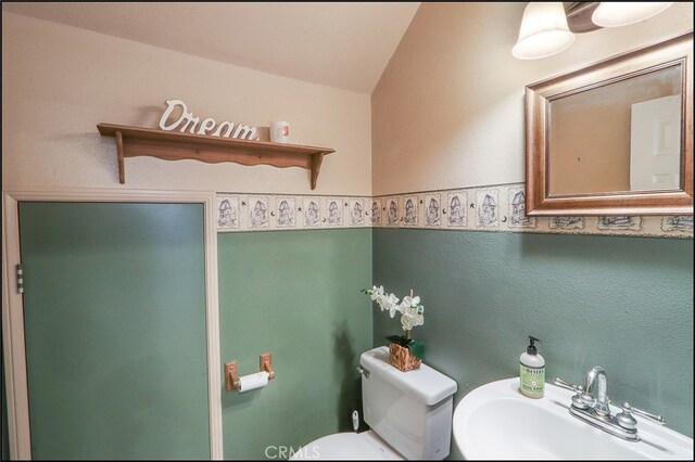 half bath featuring toilet, a sink, and a textured wall