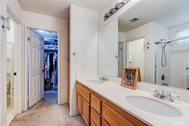 full bathroom with a walk in closet, double vanity, a sink, and an enclosed shower