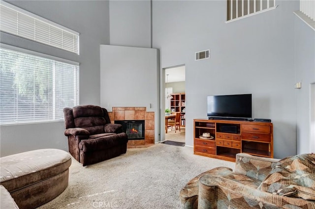 living room featuring carpet, a high ceiling, visible vents, and a tile fireplace