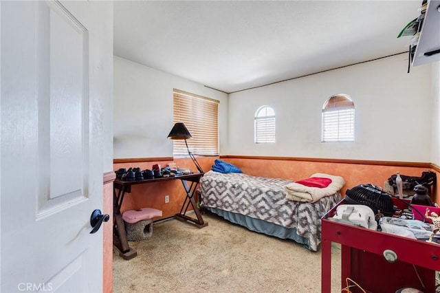 carpeted bedroom featuring a wainscoted wall