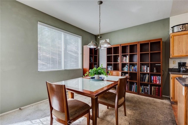 dining room featuring a notable chandelier, baseboards, and light colored carpet