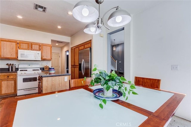 kitchen with white appliances, dark countertops, visible vents, and tasteful backsplash