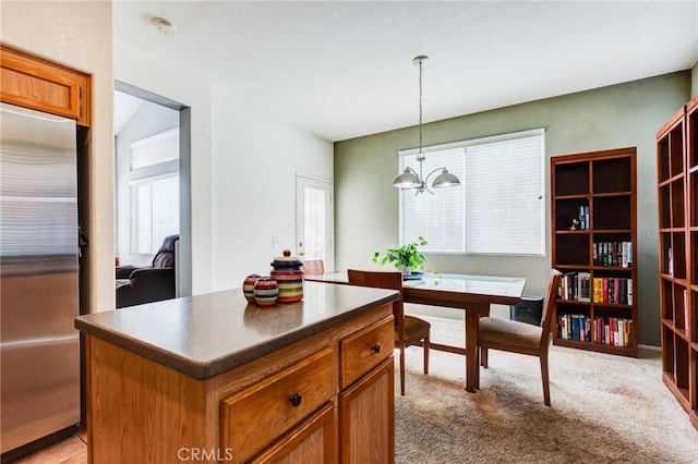 kitchen with brown cabinetry, a center island, built in refrigerator, a chandelier, and pendant lighting