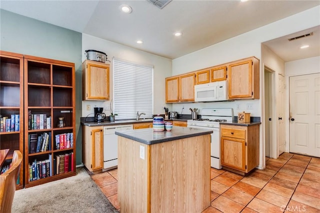 kitchen with white appliances, dark countertops, visible vents, and a center island