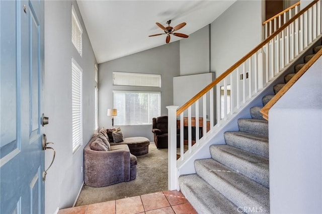 entryway with high vaulted ceiling, light carpet, stairway, and light tile patterned floors