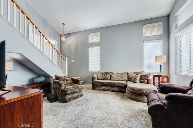 carpeted living area featuring a high ceiling and stairway