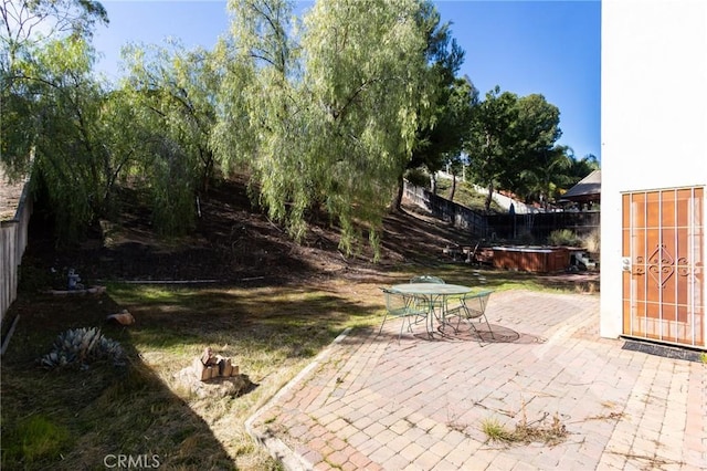 view of patio / terrace featuring outdoor dining area, a fenced backyard, and a jacuzzi