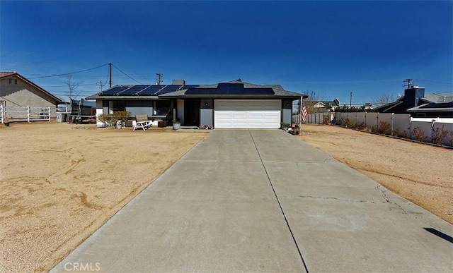 ranch-style home with driveway, an attached garage, fence, and roof mounted solar panels