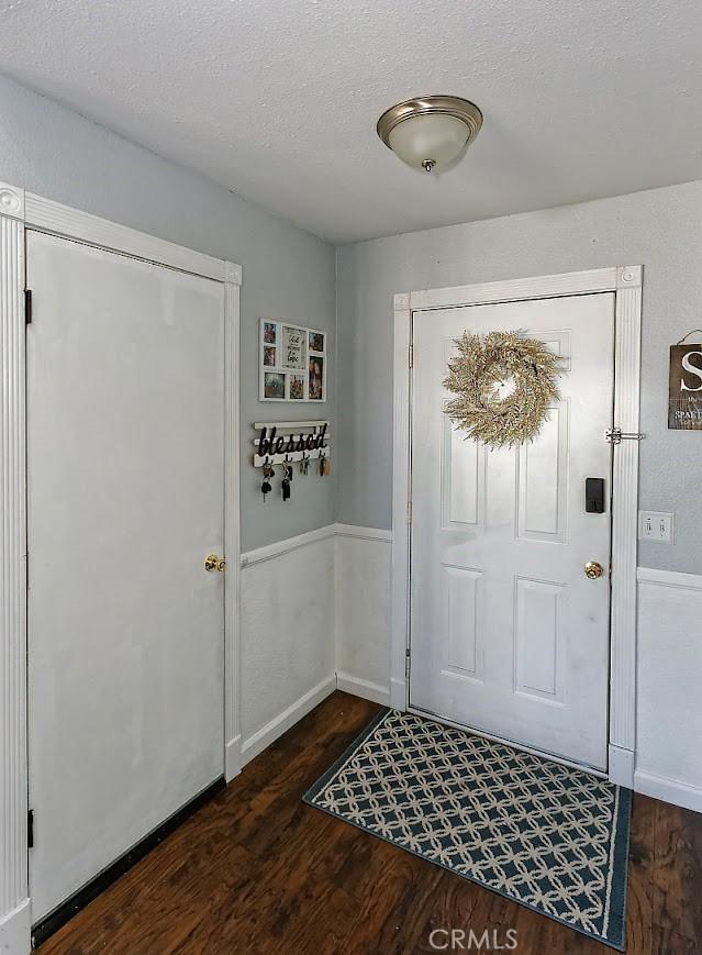 foyer with dark wood-style floors and a textured ceiling