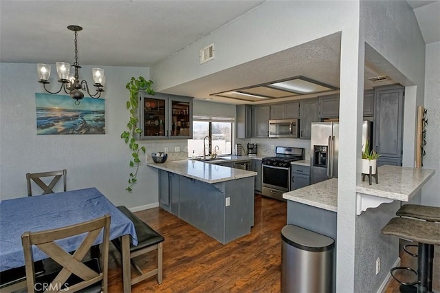 kitchen with a peninsula, appliances with stainless steel finishes, glass insert cabinets, and a kitchen breakfast bar