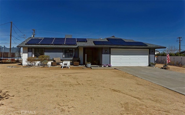 single story home with an attached garage, fence, driveway, roof mounted solar panels, and a trampoline