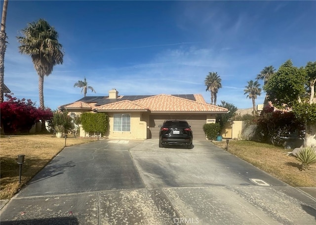 ranch-style house featuring an attached garage, solar panels, a tile roof, concrete driveway, and stucco siding