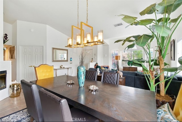 68820 San Felipe Rd, Cathedral City, CA 92234 - tiled dining space featuring a chandelier, a glass covered fireplace, and vaulted ceiling