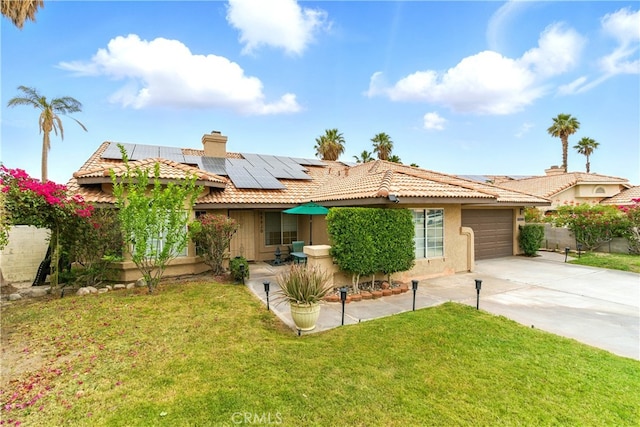 68820 San Felipe Rd, Cathedral City, CA 92234 - view of front of home with concrete driveway, a garage, stucco siding, roof mounted solar panels, and a front lawn