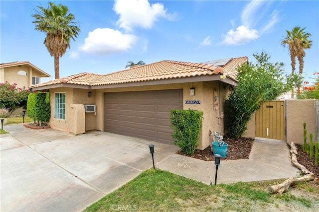 68820 San Felipe Rd, Cathedral City, CA 92234 - view of front facade with stucco siding, a tile roof, a gate, roof mounted solar panels, and an attached garage
