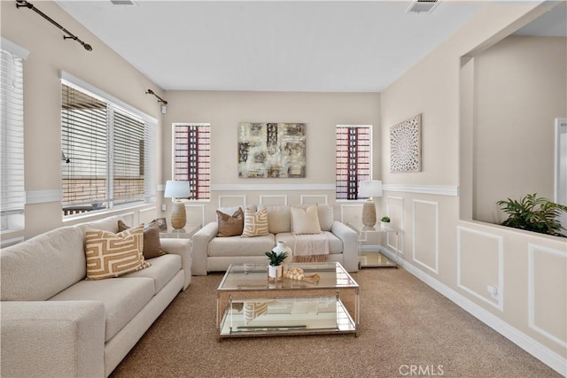 living room with carpet floors, a wainscoted wall, visible vents, and a decorative wall