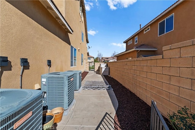 view of property exterior with a patio, stucco siding, and central air condition unit