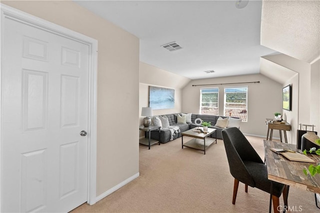 living area featuring light colored carpet, visible vents, vaulted ceiling, and baseboards