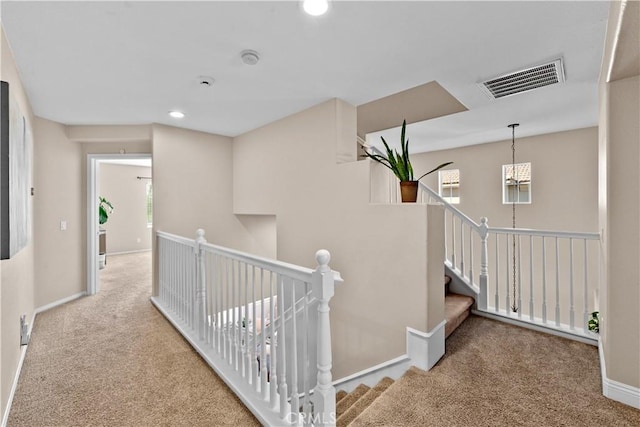 hall featuring recessed lighting, an upstairs landing, visible vents, baseboards, and carpet