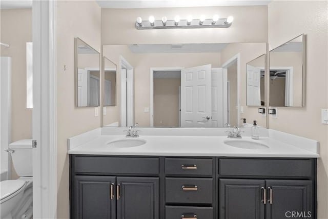 full bathroom featuring toilet, double vanity, walk in shower, and a sink